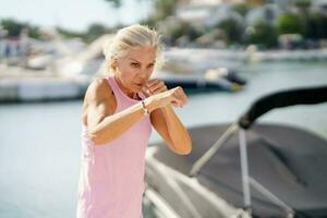 Mature woman doing shadow boxing outdoors. Senior female doing sport in a coastal port photo