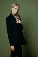 An attractive cool professional model holds a jacket by the lapel collar and poses on a green olive background in the studio. Cool banner for brands photo