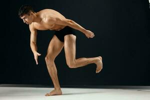 male bodybuilder with muscular body in black shorts posing dark background photo