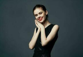 Elegant lady in a black dress on a gray background gestures with her hands emotions surprise joy photo