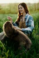 contento mujer sentado en naturaleza y jugando con su mascota en el parque sentado en el verde césped foto