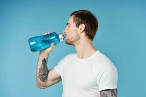 deportivo hombre con tatuajes en su brazos azul rutina de ejercicio agua botella foto