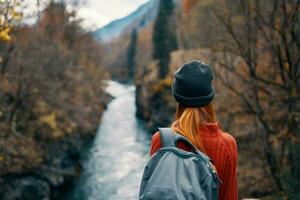 mujer con mochila en naturaleza en el puente cerca el río montañas aventuras foto