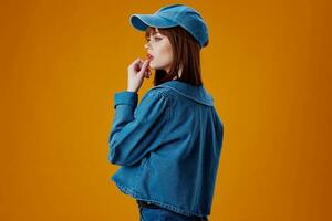 Portrait of a charming lady in a cap and denim jacket posing color background unaltered photo