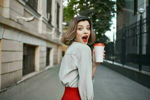 bonito mujer rojo falda café taza al aire libre caminar foto