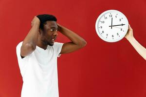 hombre en sorpresa mira a su reloj en un blanco camiseta foto