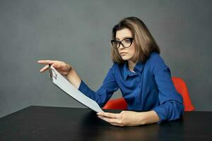 woman in a blue shirt sits at the table folder in hands Copy Space photo