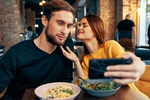 joven Pareja en un restaurante hace un selfie en el teléfono comunicación foto