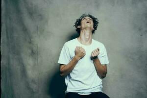 happy curly guy in a t-shirt gesturing with his hands on a fabric background in a studio photoshoot model photo