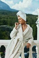 Portrait of gorgeous woman in a white robe on the balcony bit on green nature unaltered photo