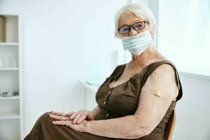 elderly woman wearing glasses with plaster on her hand covid passport hospital photo