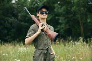 Woman soldier With a weapon in dark glasses hunting black cap photo