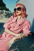 pretty woman with pink hair sitting on a chair outdoors vintage fashion photo