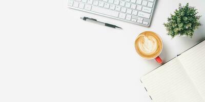 White office desk with computer keyboard, notebook, pen and cup of coffee, Top view wth copy space, Flat lay. photo