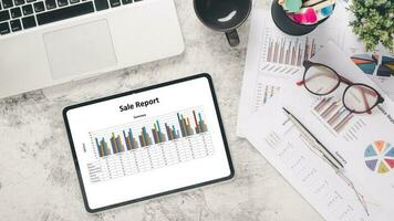 Tablet with charts and reports on office desk workplace. Top view flat lay. photo