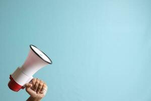 male hand holding megaphone, announcing advertisement. Isolated image on blue background photo