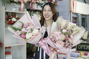 One cheerful female florist worker showing beautiful flora bouquets that receive in valentine, happy and bright smiles, arranging work in a colorful flower shop, SME business entrepreneur person. photo