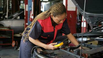 uno negro hembra profesional automotor mecánico trabajador cheques un ev coche batería y híbrido motor a un mantenimiento cochera, experto eléctrico vehículo servicio, y fijación ocupaciones auto industria. foto