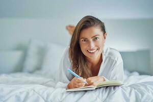 Brunette woman on bad with notepad or book photo