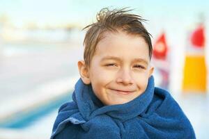 Picture of young boy in towel after playing in outdoor aqua park photo