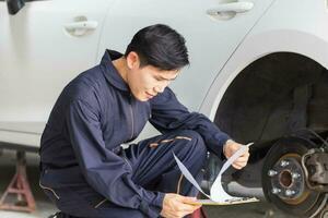 Auto mechanic repairman with a checklist, Technician checking modern car at garage, Car repair and maintenance concepts photo