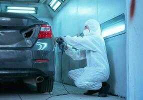 Mechanic man works with grinding tool. Sanding of car elements. Garage painting car service repair and maintenance photo