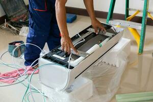 técnico hombre instalando un aire acondicionamiento en un cliente casa, reparador fijación aire acondicionador unidad, mantenimiento y reparando conceptos foto