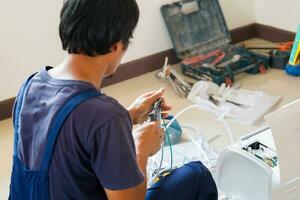 Asian technician man installing air conditioning in client house, Young repairman fixing air conditioner unit, Maintenance and repairing concepts photo