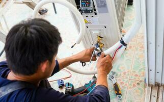 Male technician fixing modern air conditioner, Electrician installing air conditioner unit, Repairman installing an air conditioner unit in a client house, Maintenance and repairing concepts photo