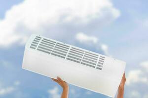 Hand lifting air conditioner unit with clipping path over blurred background photo