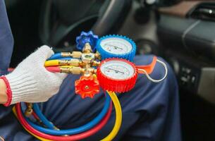 Repairman holding monitor tool to check and fixed car air conditioner system, Technician check car air conditioning system refrigerant recharge, Air Conditioning Repair photo