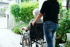 Caregiver help Asian elderly woman disability patient sitting on wheelchair in hospital, medical concept. photo