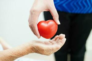 Asian young boy give red heart to old grandmother with love and care. photo