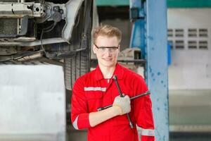 alegre el mecánico hombre en reparar cochera, técnico hombre trabajando en auto reparar comercio, coche reparar y mantenimiento conceptos foto