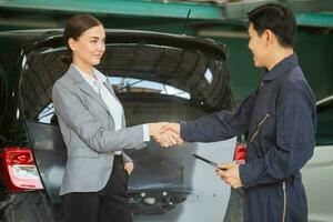 Mechanic man shaking hands with customer at the repair garage. Auto mechanic shaking hands with young woman client, Car repair and maintenance concepts photo