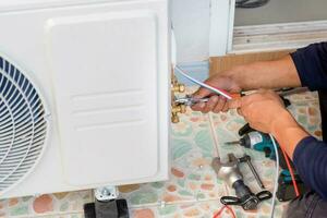 Technician man installing air conditioning in a client house, Repairman fixing air conditioner unit, Maintenance and repairing concepts photo