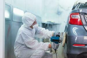 mecánico hombre trabajos con molienda herramienta. lijado de coche elementos. garaje pintura coche Servicio reparar y mantenimiento foto