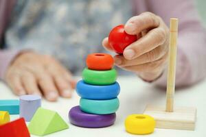 asiático mayor mujer jugando rompecabezas juego a práctica cerebro formación para demencia prevención, Alzheimer enfermedad. foto