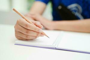 asiático Adolescente estudiante escribir tarea, estudiar lección para examen en línea aprendizaje educación. foto