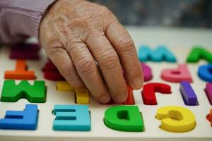 Asian elderly woman playing puzzles game to practice brain training for dementia prevention, Alzheimer disease. photo