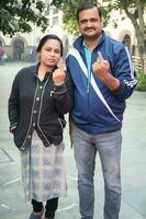 New Delhi, India - March 04 2023 - Unidentified people showing their ink-marked fingers after casting votes in front of polling booth of east Delhi area for MCD local body Elections 2022 photo