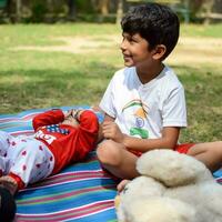 dos contento Niños en sociedad parque, contento asiático hermanos quien son sonriente felizmente juntos. hermanos jugar al aire libre en verano, mejor amigos. niñito bebé chico jugando con su contento hermano en el jardín foto