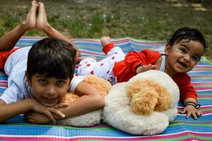 Two happy boys in society park, happy Asian brothers who are smiling happily together. Brothers play outdoors in summer, best friends. Toddler baby boy playing with his happy brother in the garden photo