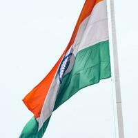 India flag flying high at Connaught Place with pride in blue sky, India flag fluttering, Indian Flag on Independence Day and Republic Day of India, tilt up shot, Waving Indian flag, Har Ghar Tiranga photo