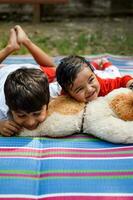 dos contento Niños en sociedad parque, contento asiático hermanos quien son sonriente felizmente juntos. hermanos jugar al aire libre en verano, mejor amigos. niñito bebé chico jugando con su contento hermano en el jardín foto