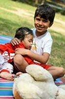 Two happy boys in society park, happy Asian brothers who are smiling happily together. Brothers play outdoors in summer, best friends. Toddler baby boy playing with his happy brother in the garden photo