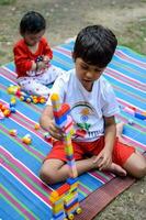 dos contento Niños en sociedad parque, contento asiático hermanos quien son sonriente felizmente juntos. hermanos jugar al aire libre en verano, mejor amigos. niñito bebé chico jugando con su contento hermano en el jardín foto