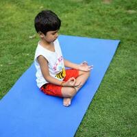 Asian smart kid doing yoga pose in the society park outdoor, Children's yoga pose. The little boy doing Yoga and meditation exercise. photo