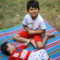 dos contento Niños en sociedad parque, contento asiático hermanos quien son sonriente felizmente juntos. hermanos jugar al aire libre en verano, mejor amigos. niñito bebé chico jugando con su contento hermano en el jardín foto