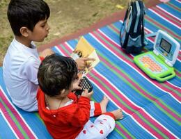 Two happy boys in society park, happy Asian brothers who are smiling happily together. Brothers play outdoors in summer, best friends. Toddler baby boy playing with his happy brother in the garden photo